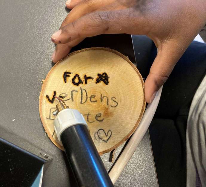 Elev brænder en tekst på et stykke træ