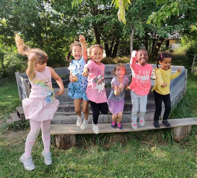 En flok glade piger på en bænk udenfor 